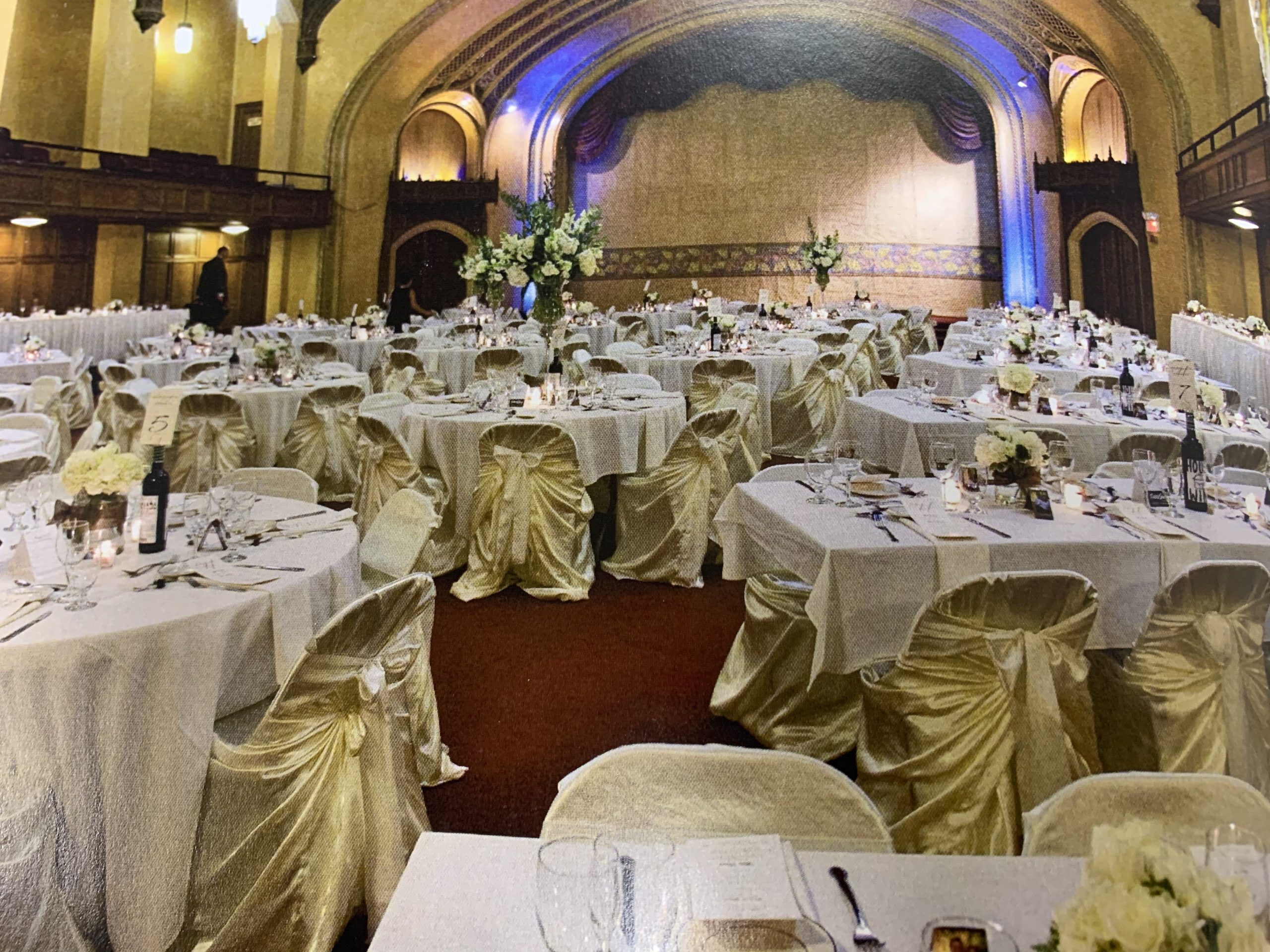 Elegant banquet hall setting adorned with elegantly draped tables and chairs, featuring floral centerpieces and soft ambient lighting, perfect for events.